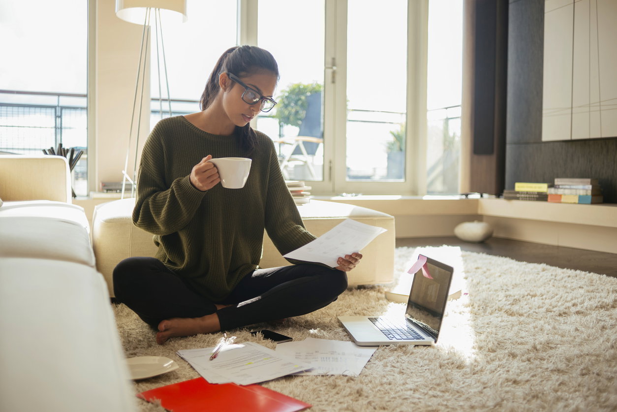 young woman reading paperwork in her living room,