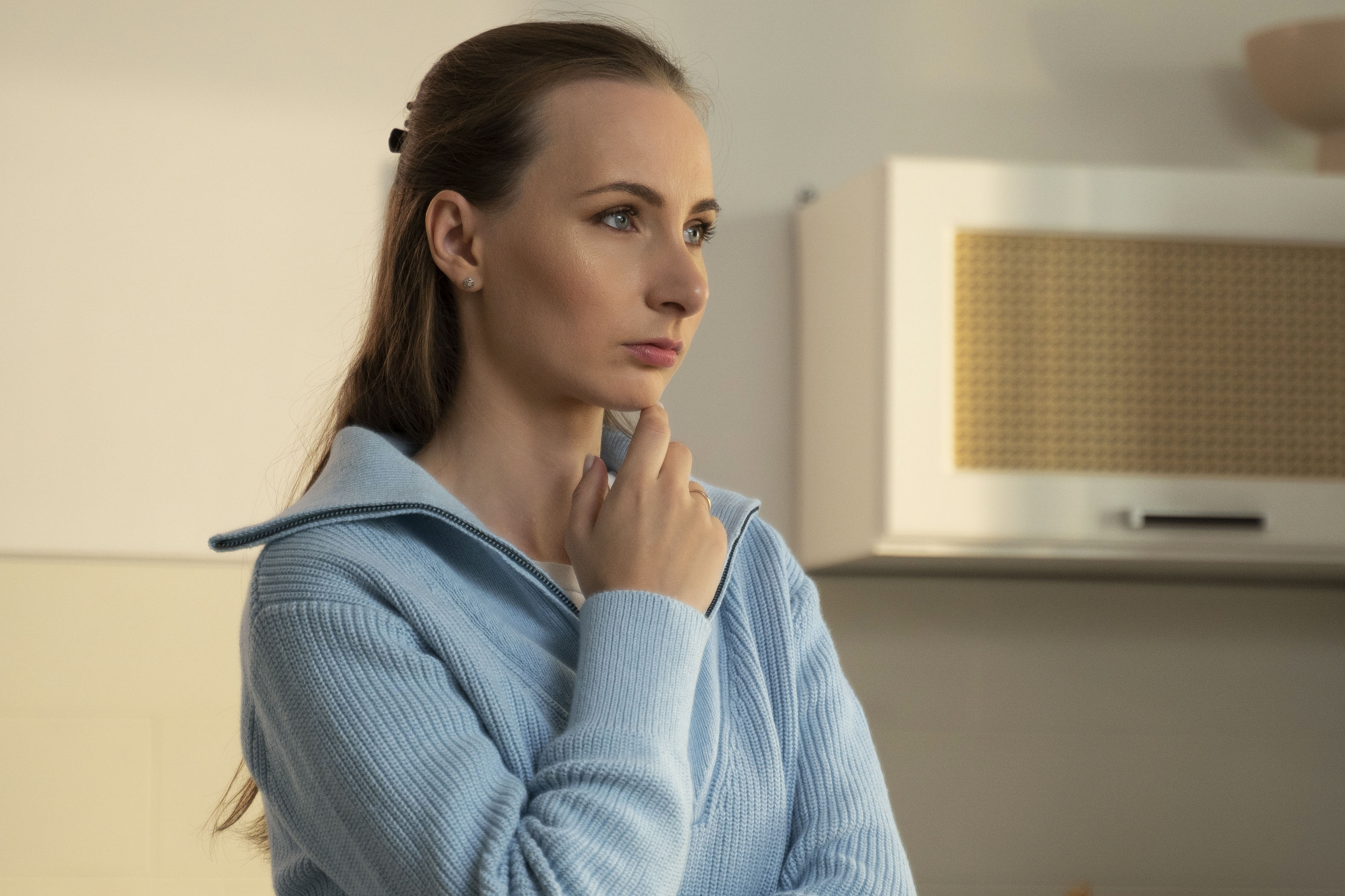 Close-up bored young woman is standing at home in the kitchen. A frustrated woman thinks about her problems indoors. She is tired, unhappy, disappointed and depressed