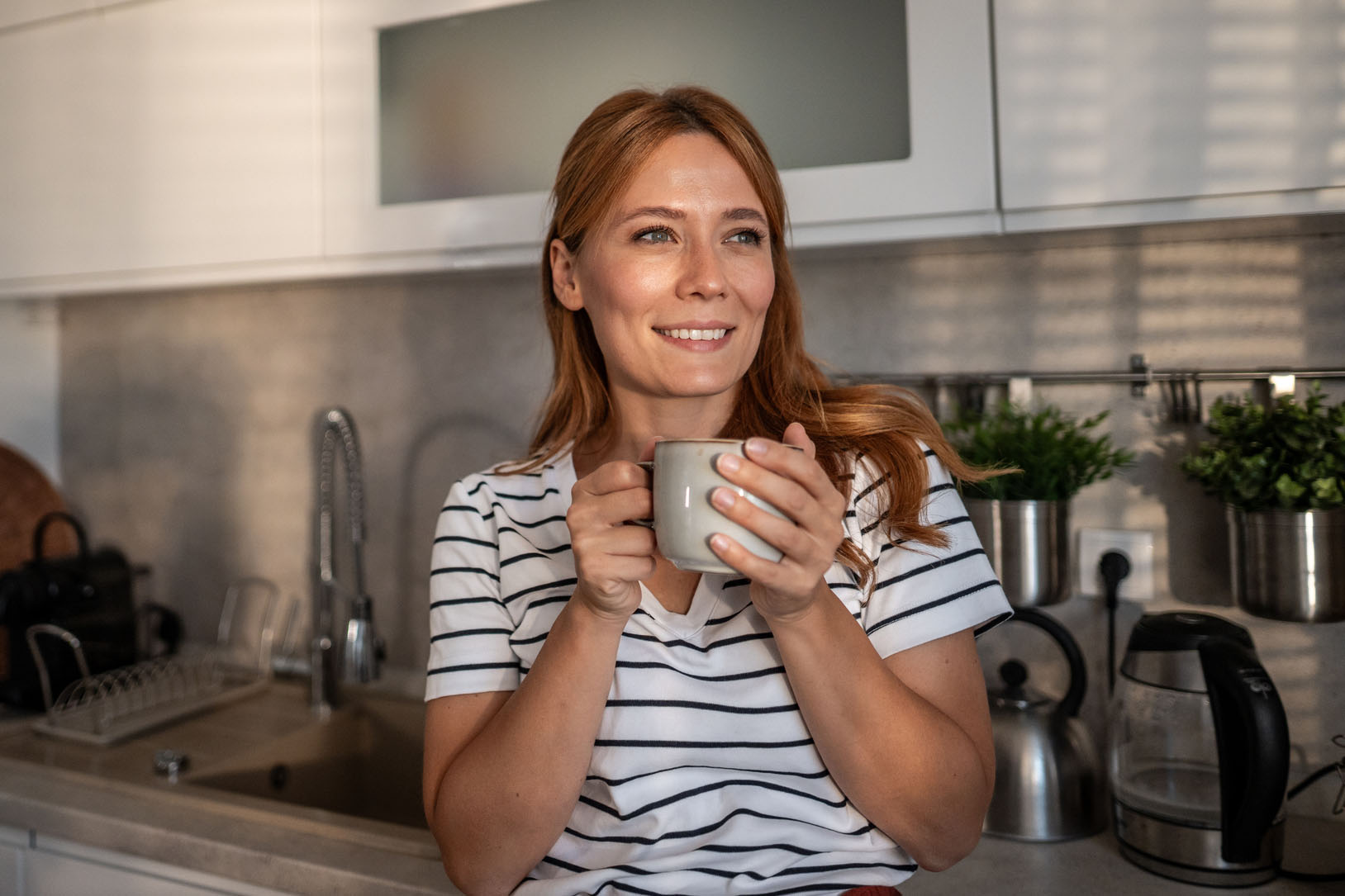 Woman enjoying morning coffee in modern kitchen