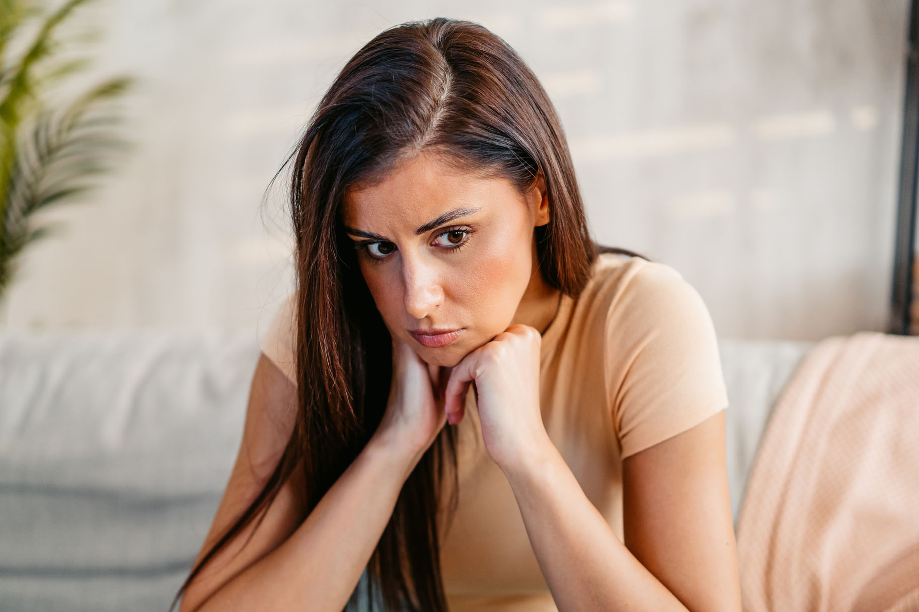 Sad Young Woman Sitting At Home On The Sofa