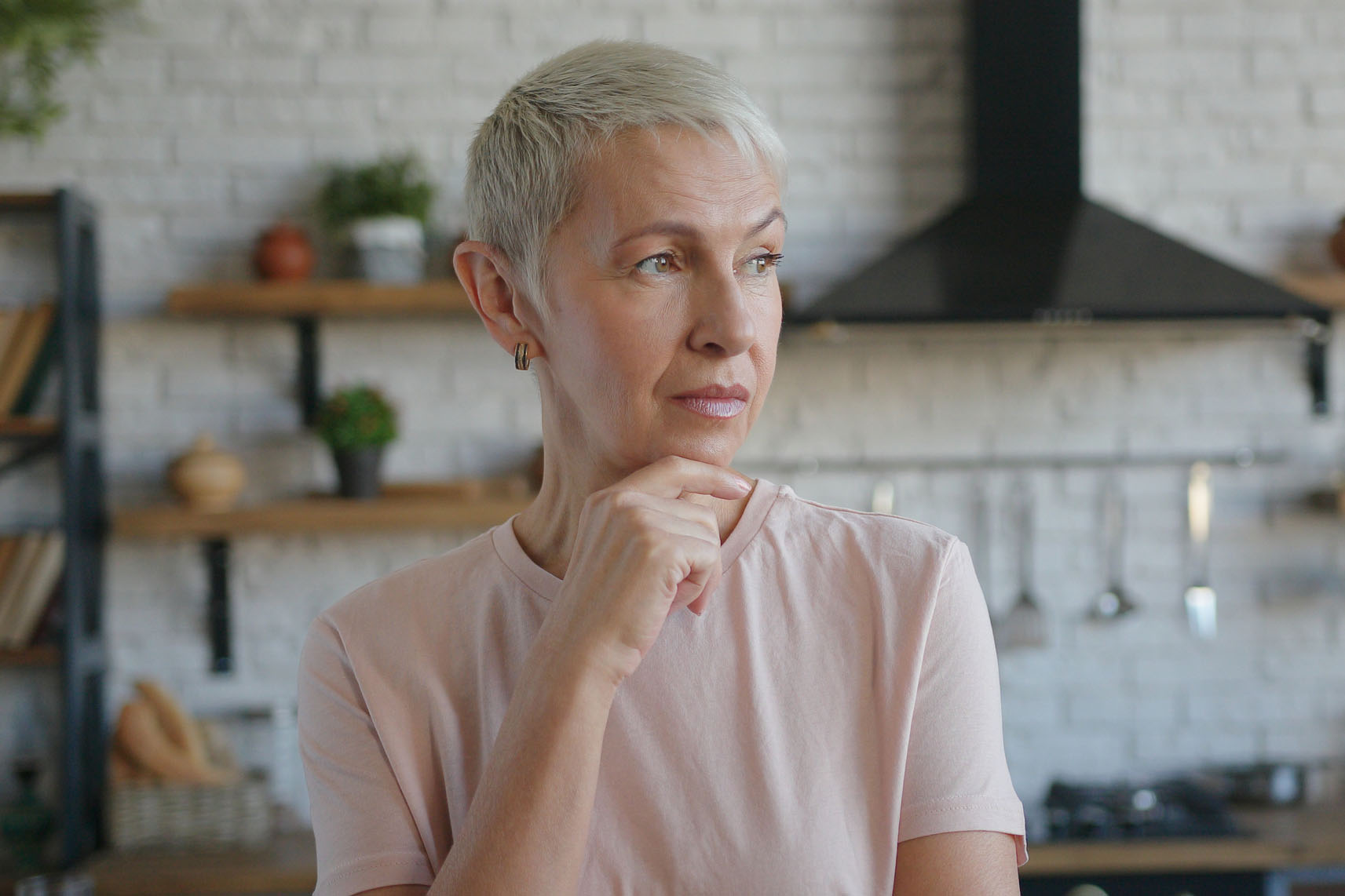 Elderly pensive woman thoughtfully at idea hold hand to chin with puzzled facial expression
