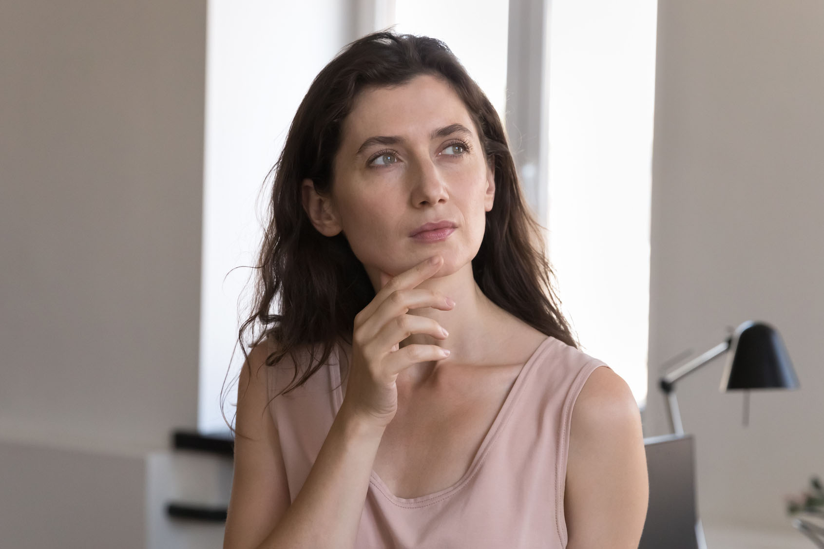 Serious young Caucasian business woman in casual standing at workplace