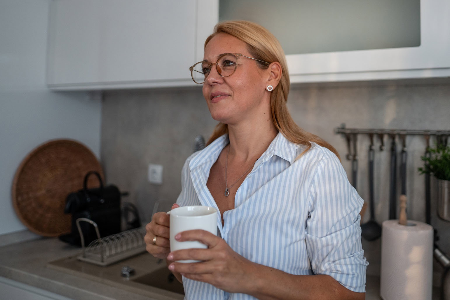 Woman enjoying morning coffee in modern kitchen