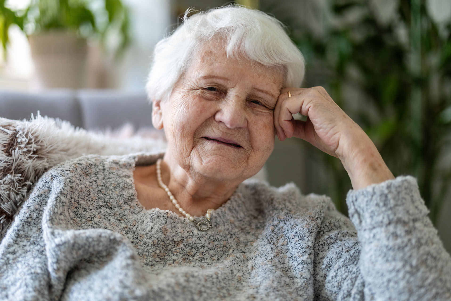 Elderly woman at her home sitting in armchair and looking at camera