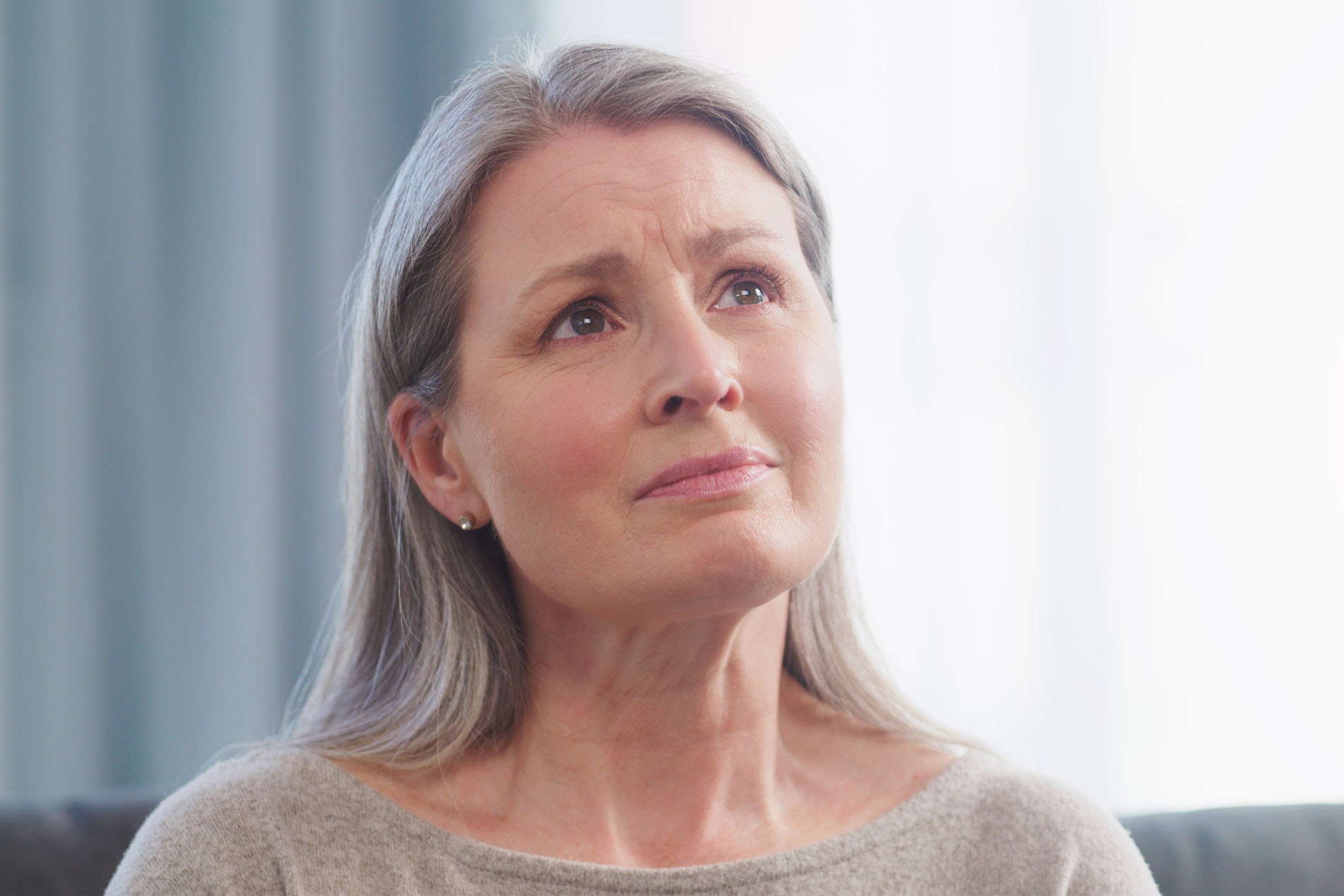 Cropped shot of an attractive senior woman looking sad while sitting on the sofa at home