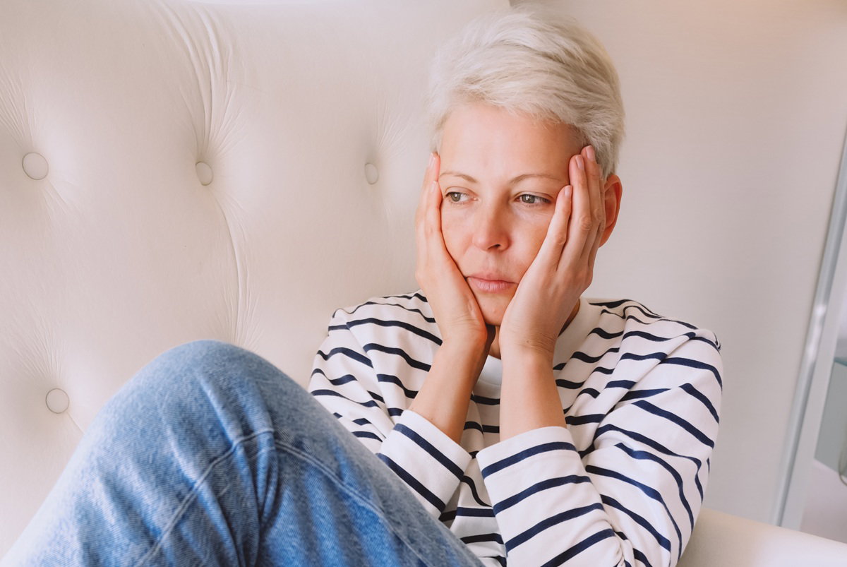 kobieta w wieku 35 plus z krótkimi jasnymi włosami siedzi w fotelu załamana