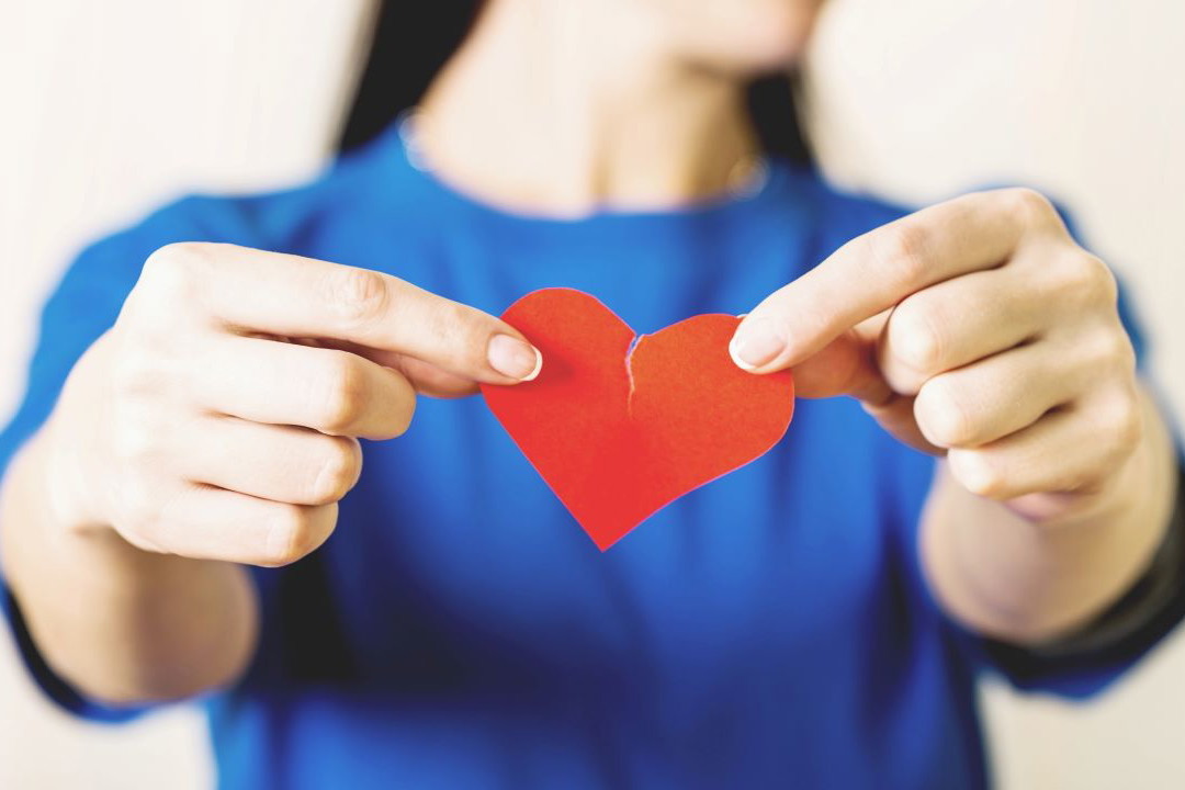 Kobieta trzymająca przerwane papierowe serca