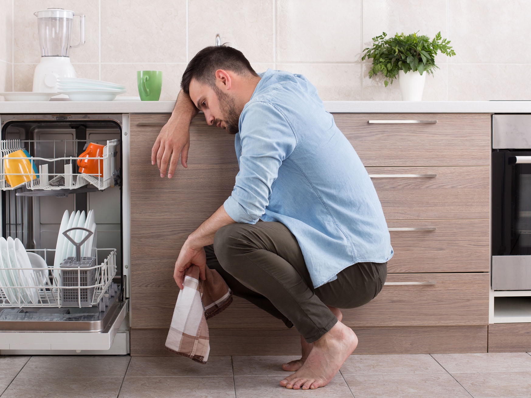 Tired man beside dishwasher