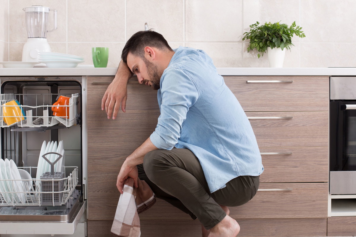 Tired man beside dishwasher