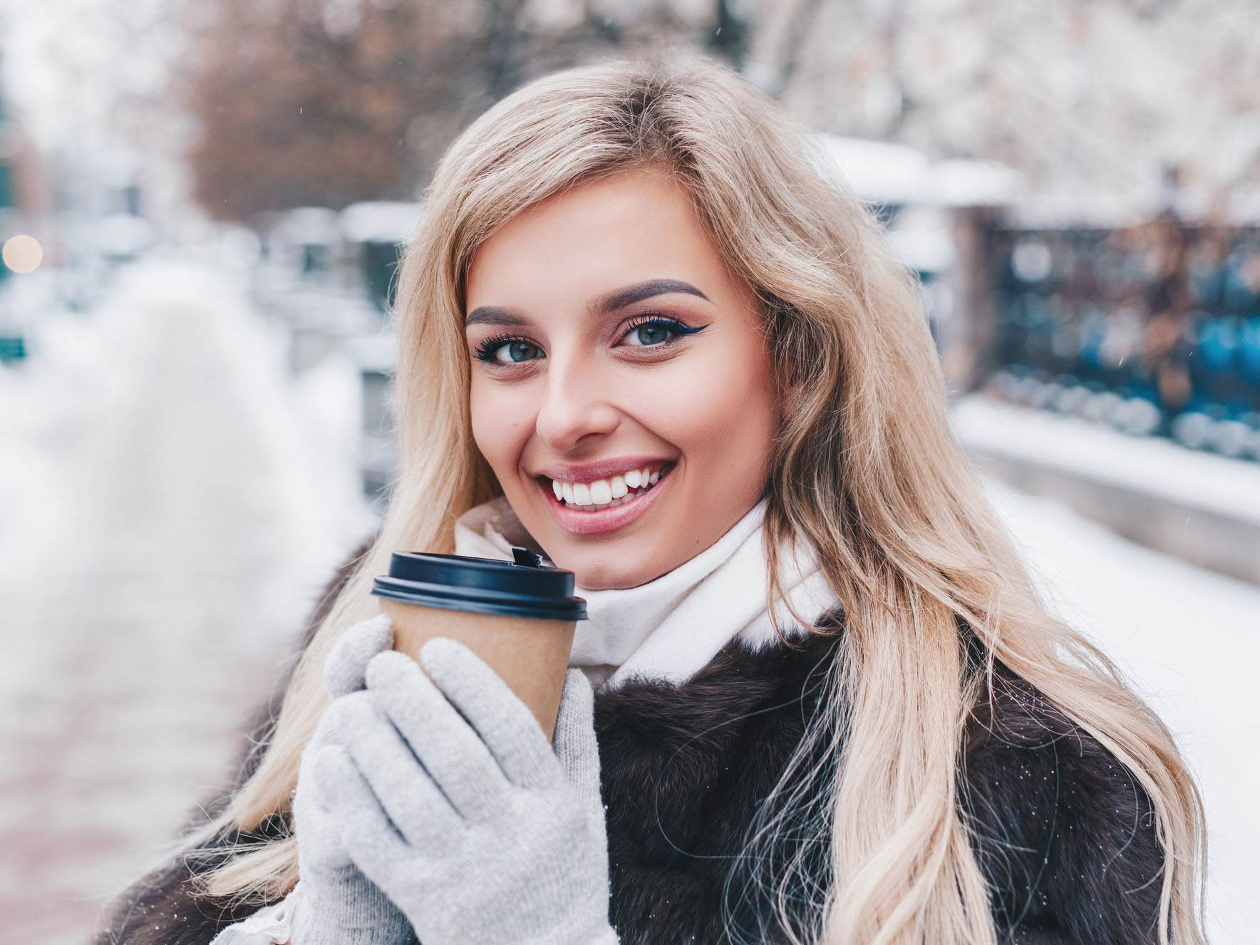 Portrait of young beautiful girl with coffee in winter street