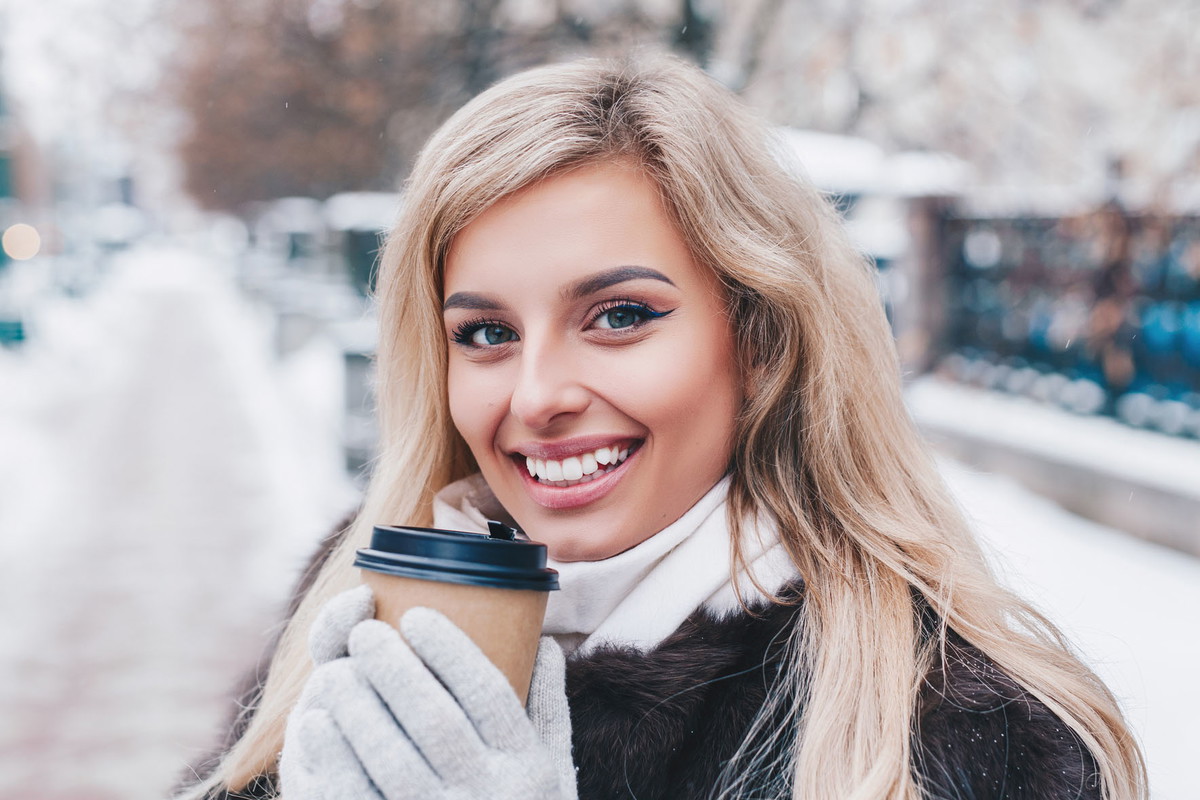 Portrait of young beautiful girl with coffee in winter street