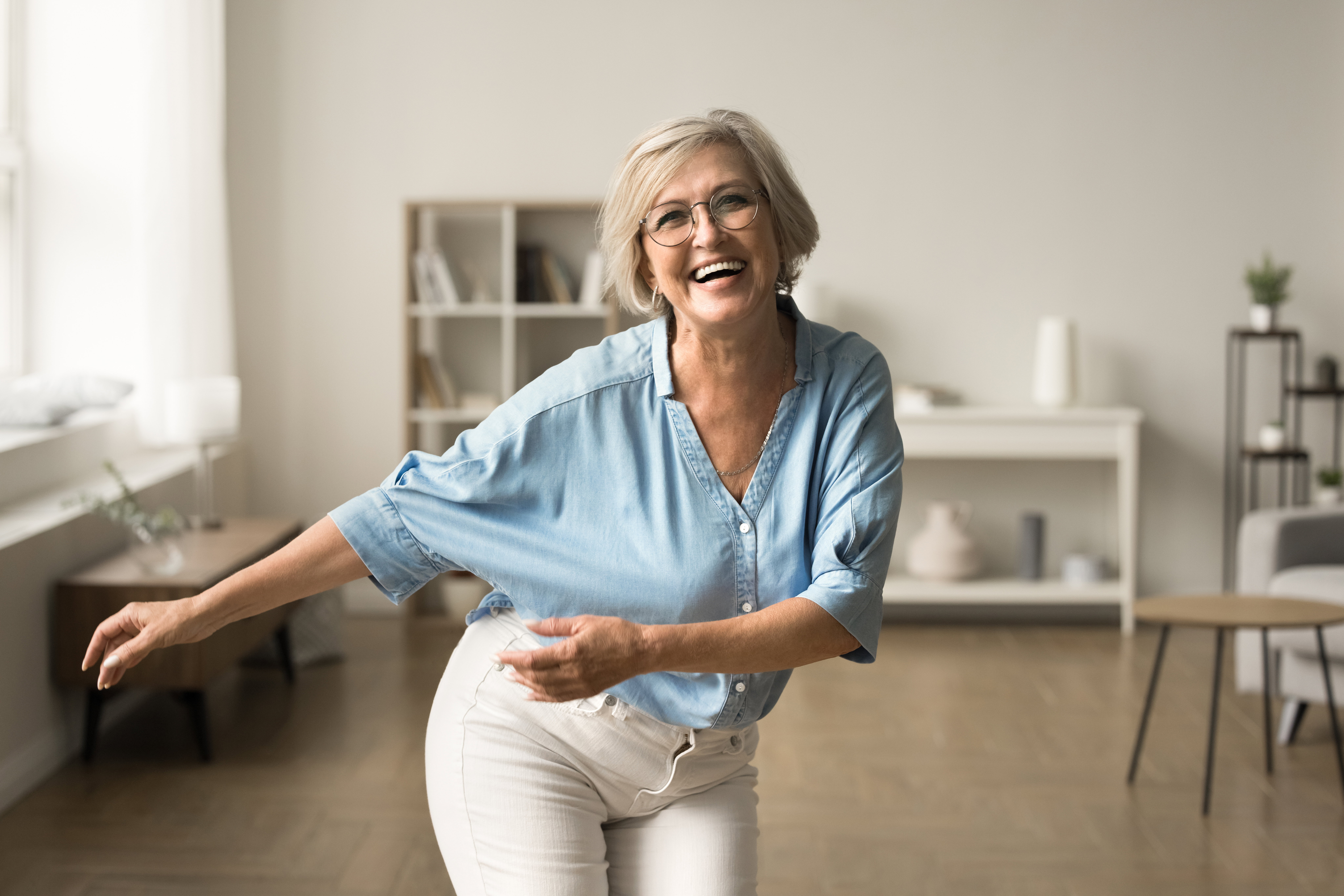 Joyful happy retired woman in glasses having fun at home