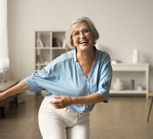 Joyful happy retired woman in glasses having fun at home