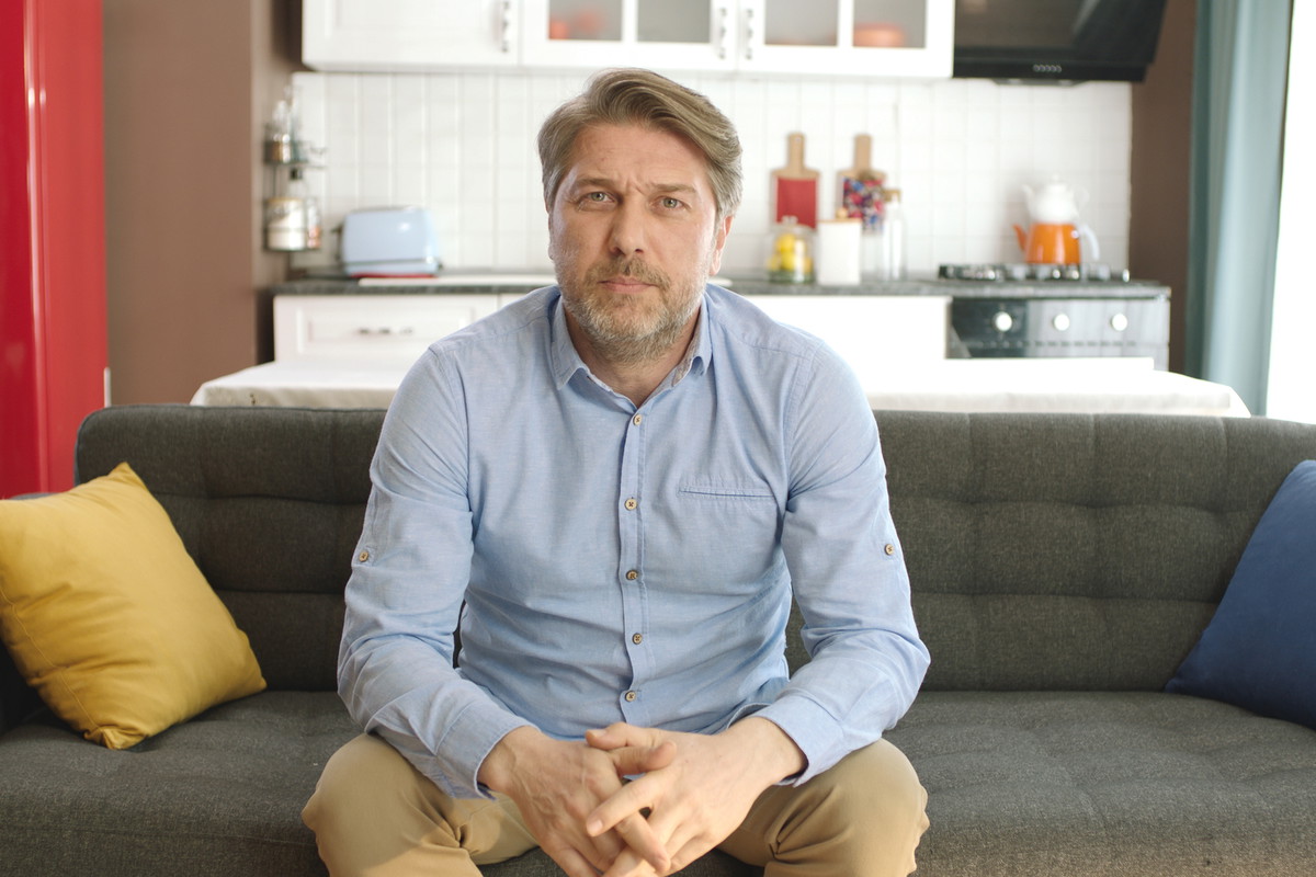 Young man looking nervously at camera while sitting on sofa at home.