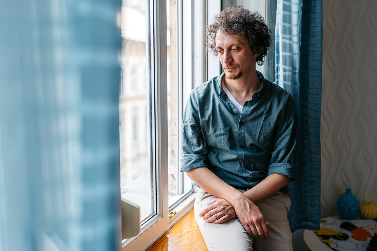 Depressed Mid-Adult Man Sitting By The Window In Budapest