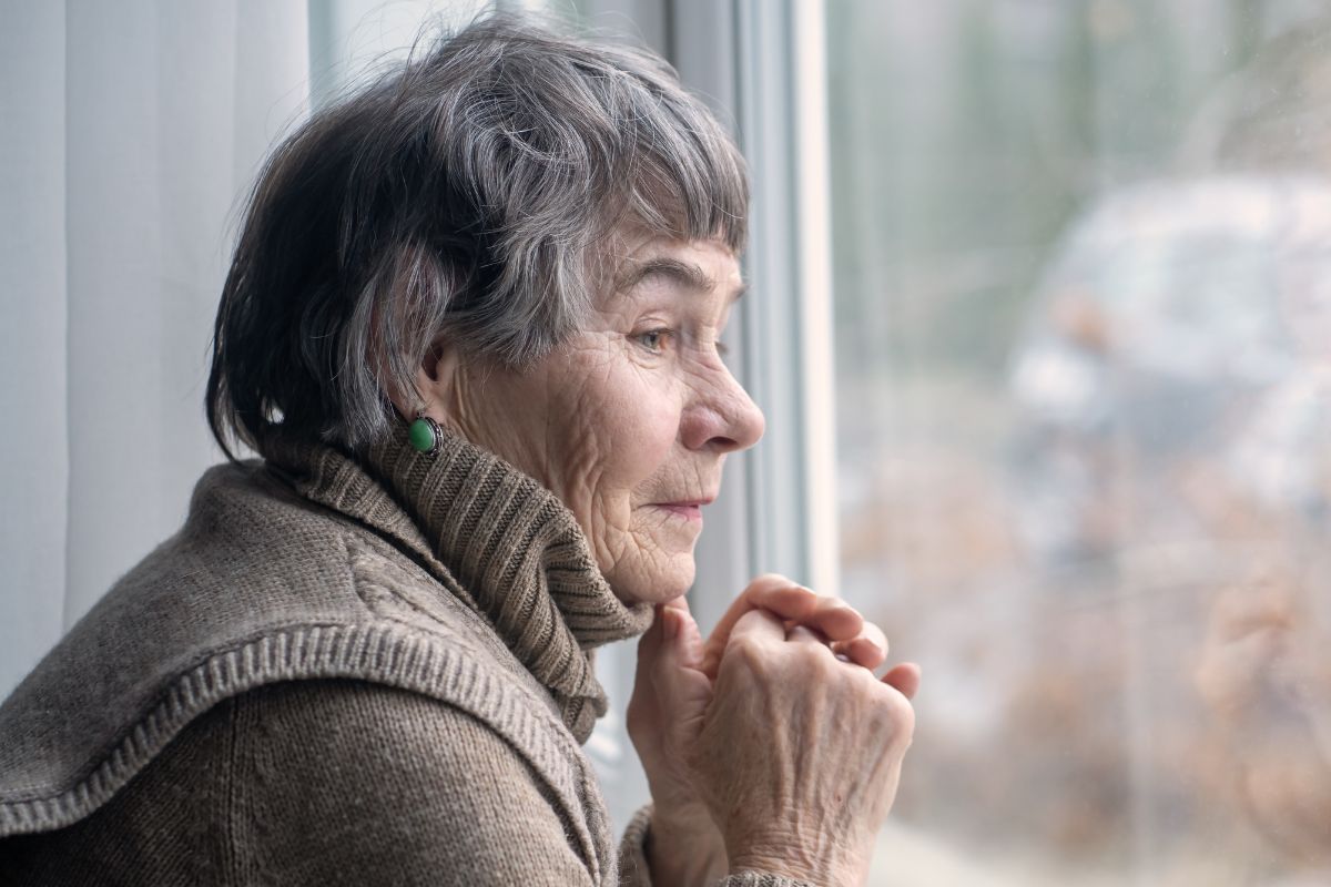 zamyślona starsza kobieta patrzy w okno