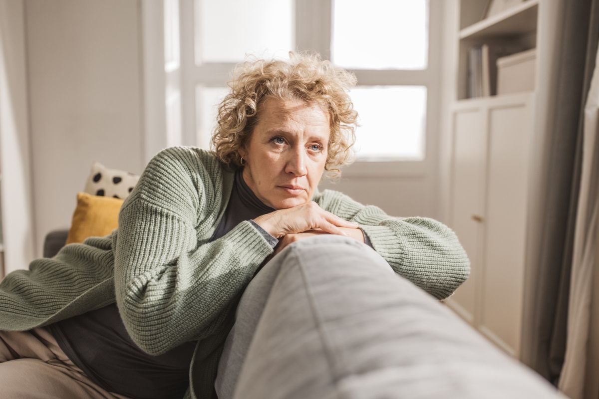 smutna kobieta oparta o sofę