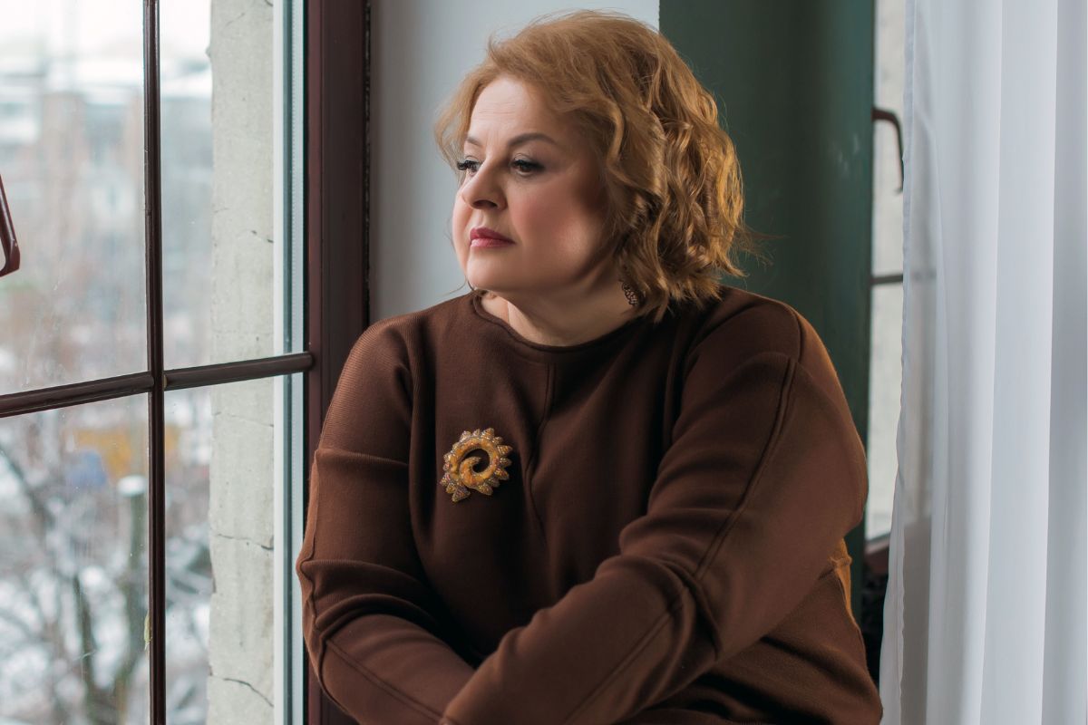 kobieta w średnim wieku wygląda przez okno