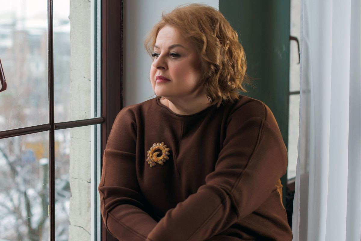 kobieta w średnim wieku wygląda przez okno