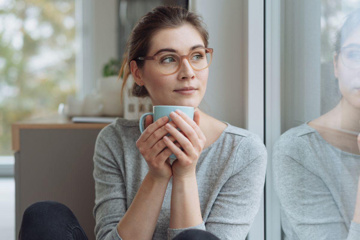 zamyślona młoda kobieta z kubkiem