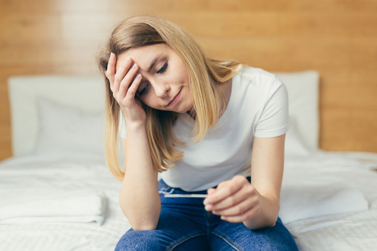 zmartwiona kobieta z testem ciążowym w ręce