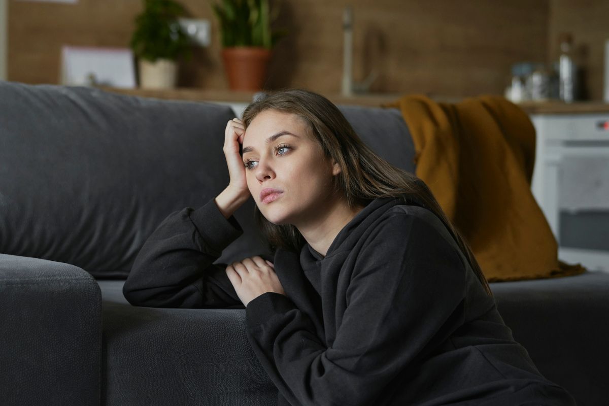 smutna kobieta opierająca się o sofę