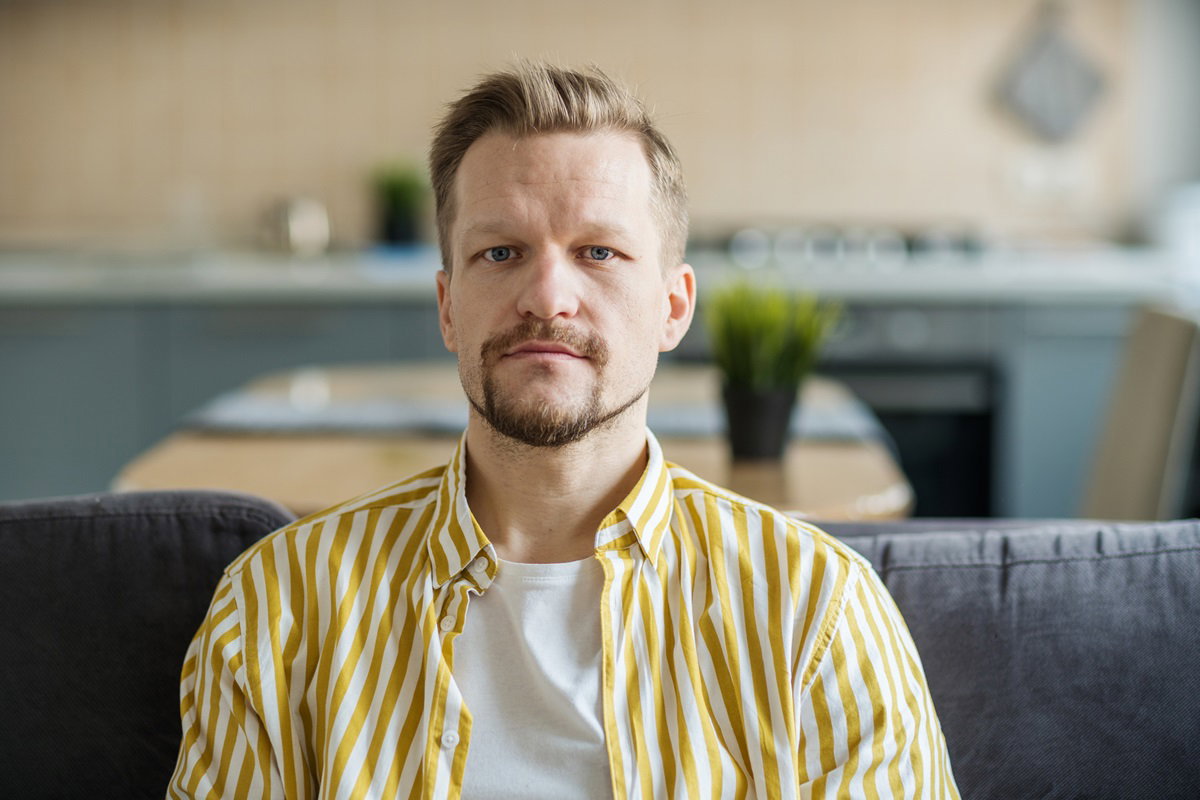 mężczyzna z blond włosami i pasiastej koszuli siedzi na kanapie