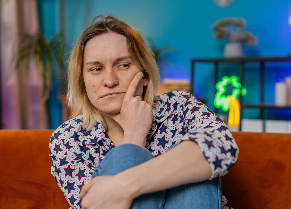 młoda kobieta wyraźnie zmartwiona siedzi na kanapie w salonie