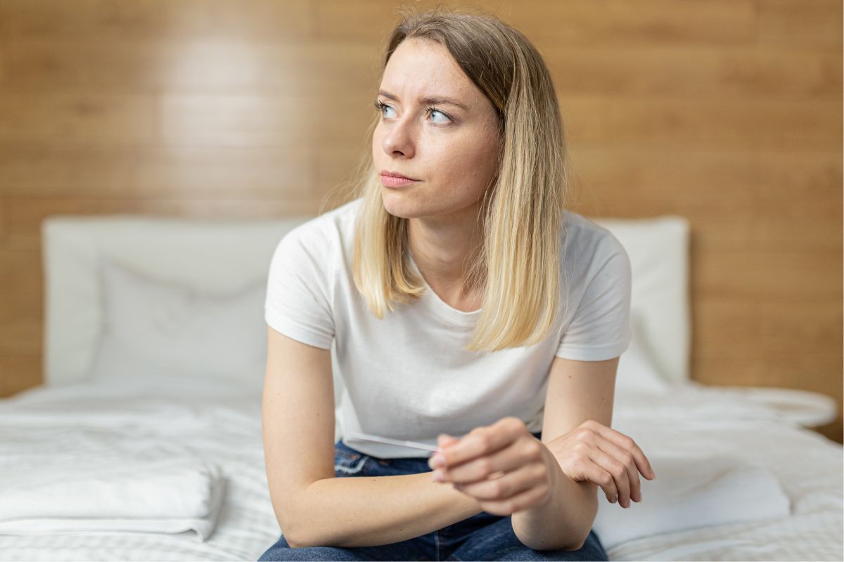 Zamyślona kobieta z testem ciążowym