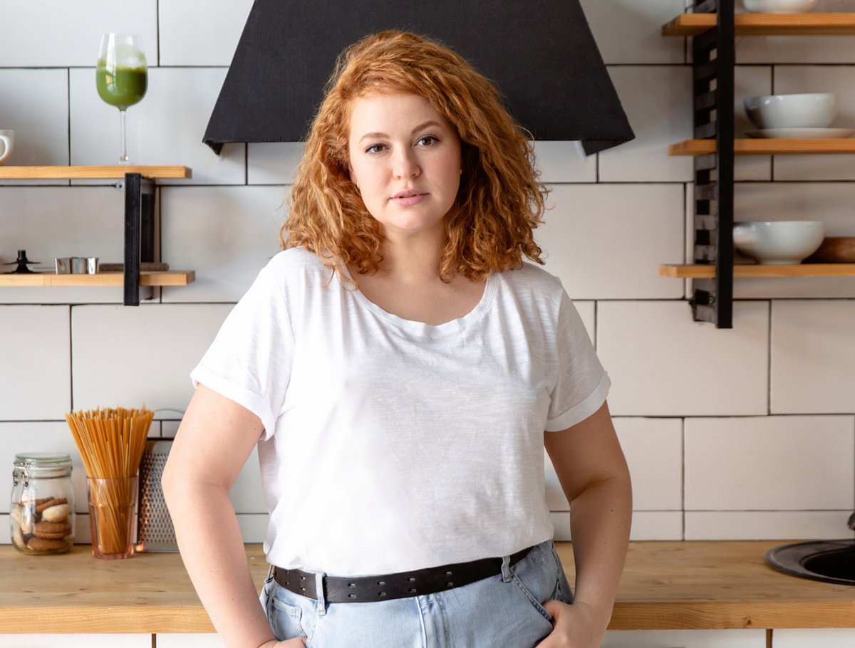 młoda kobieta z burzą rudych loków stoi na tle kuchni
