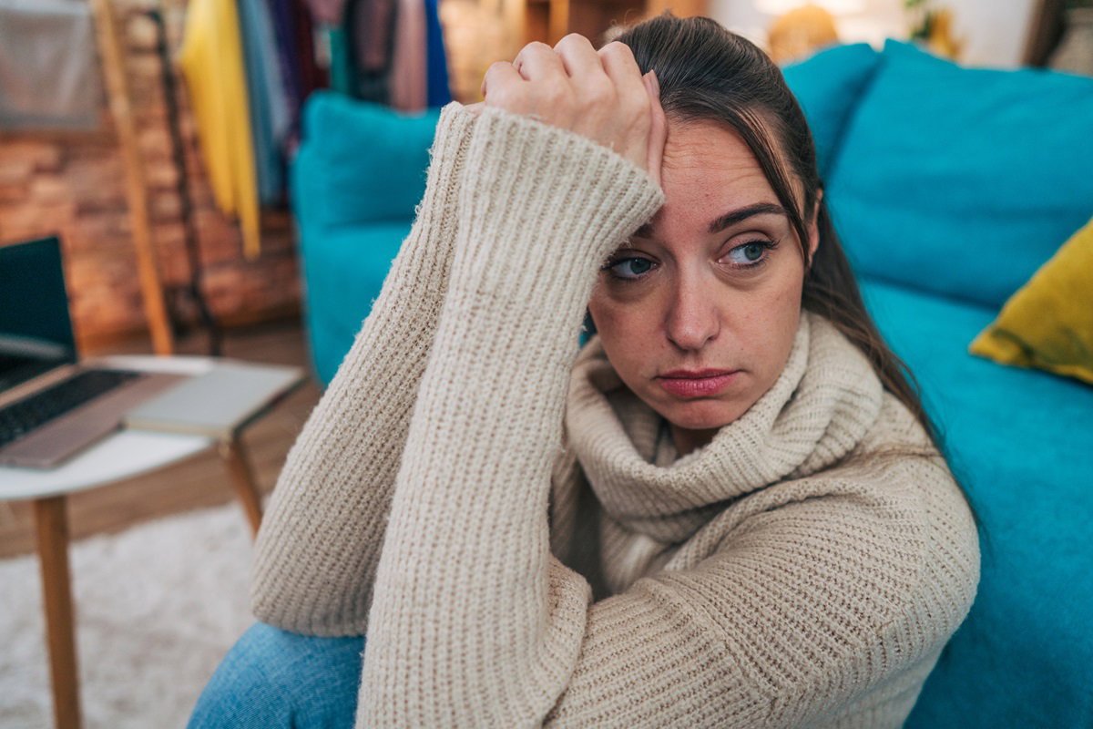 młoda kobieta rozpacza i siedzi na kanapie