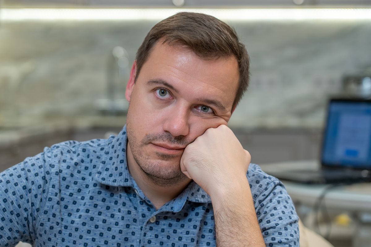 smutny i zażenowany mężczyzna siedzący w kuchni