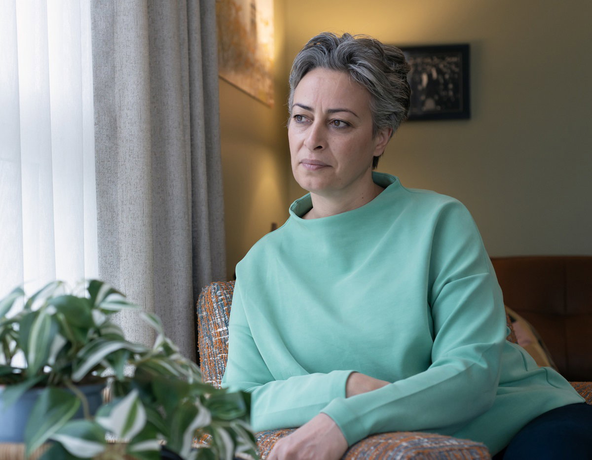 kobieta z krótkimi siwymi włosami patrzy przez okno siedząc na fotelu