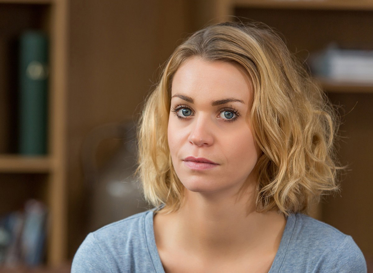 młoda kobieta z blond włosami w błękitnym t-shircie patrzy przed siebie z dezaprobatą