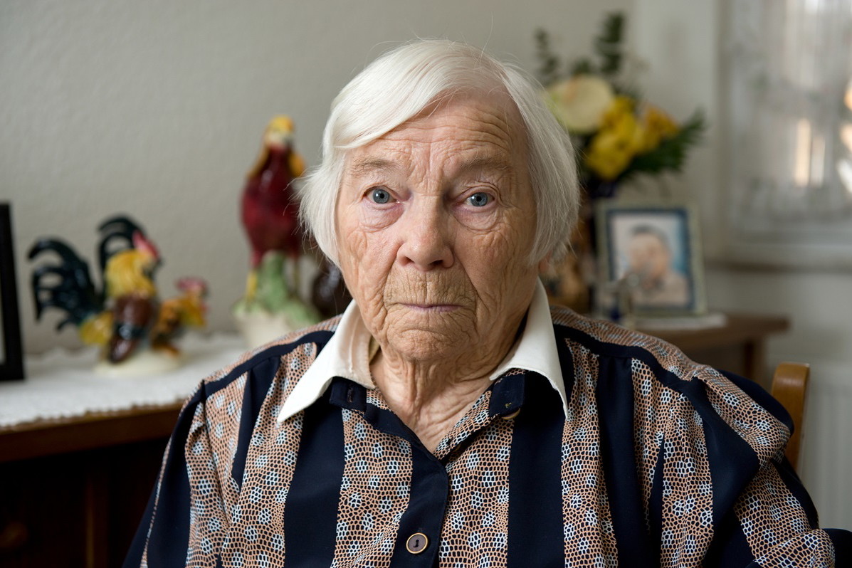 seniorka z zaciętymi ustami i smutnym wzrokiem w domu