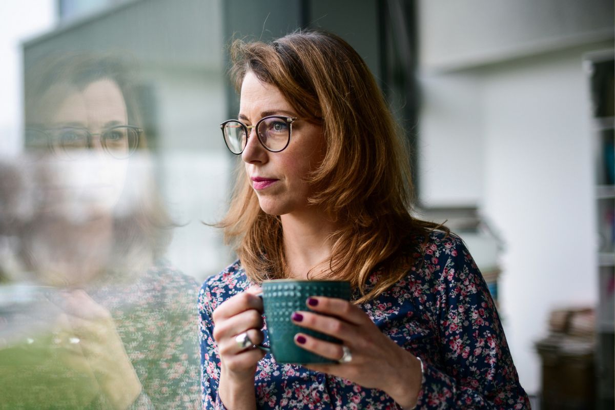 smutna kobieta stojąca przy oknie