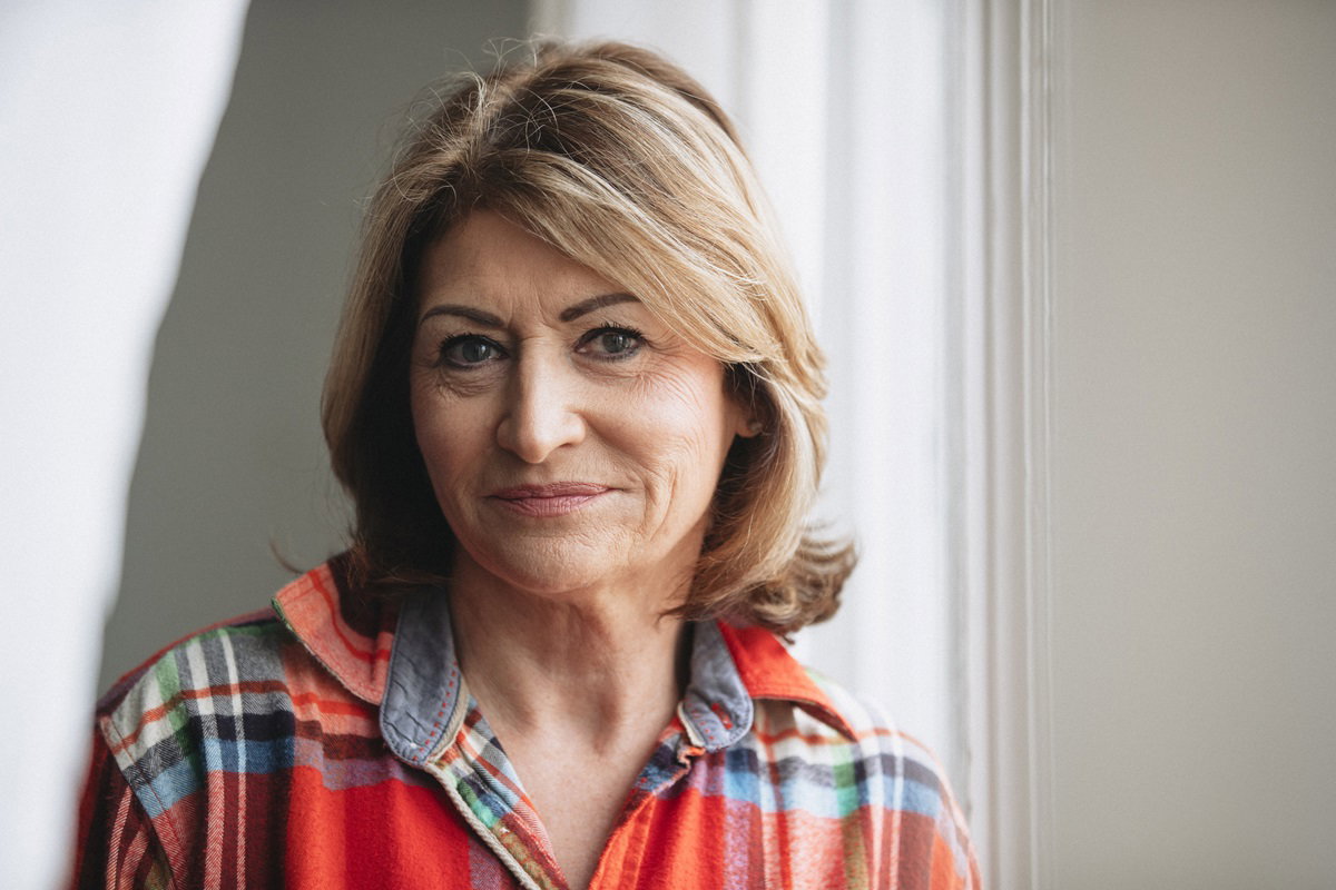 kobieta w senioralnym wieku w koszuli w kratę patrzy z uśmiechem przed siebie