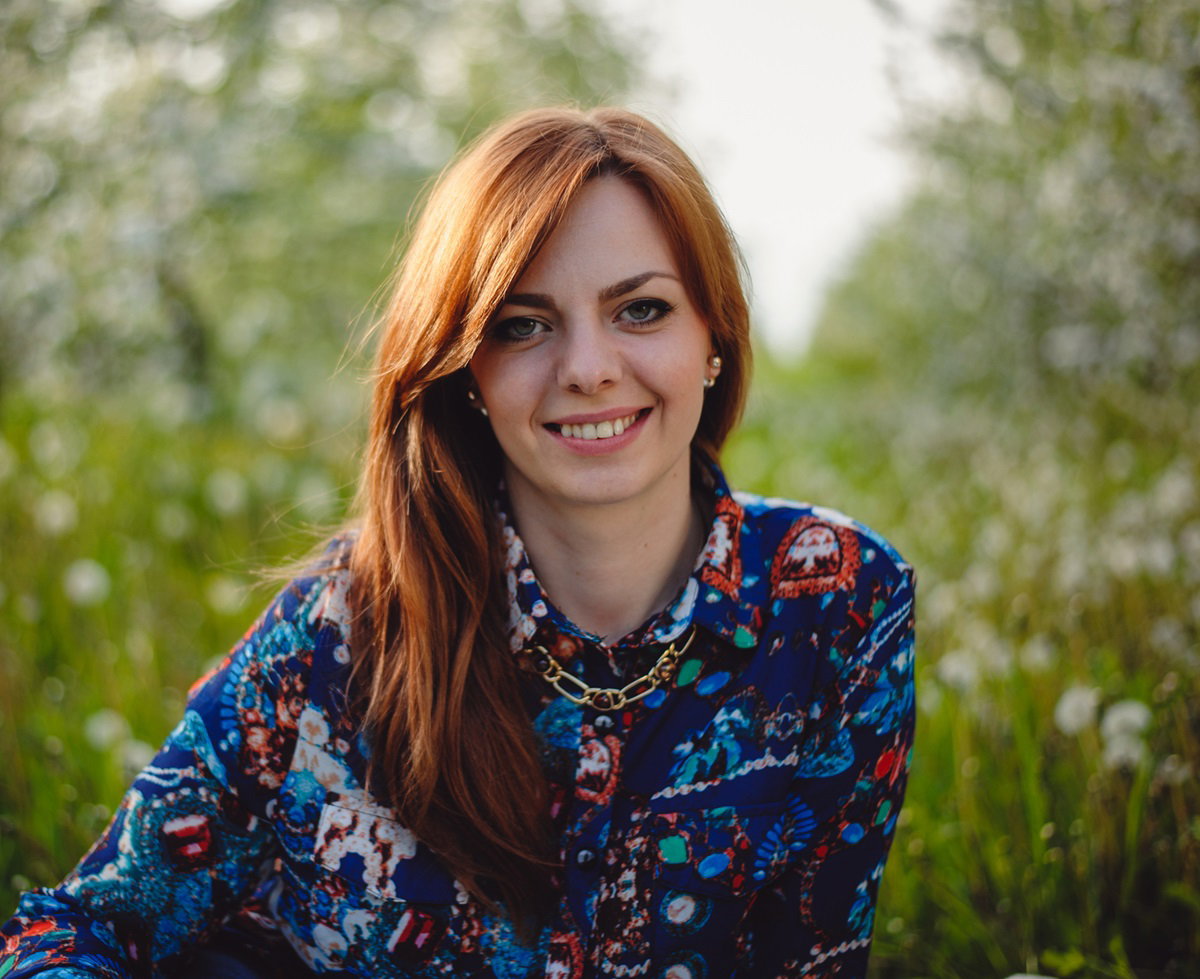 młoda dziewczyna o miedzianych włosach uśmiecha się będąc na świeżym powietrzu