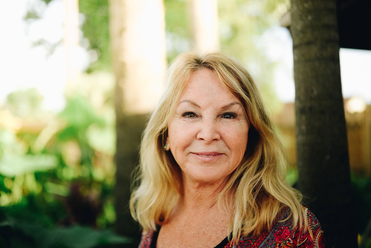 kobieta seniorka z długimi włosami uśmiecha się szeroko będąc na świeżym powietrzu