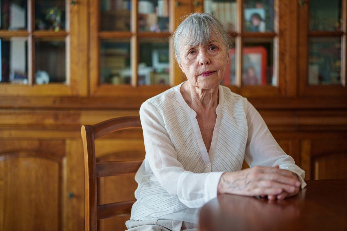 staruszka siedzi ze zmartwioną miną na tle mebli