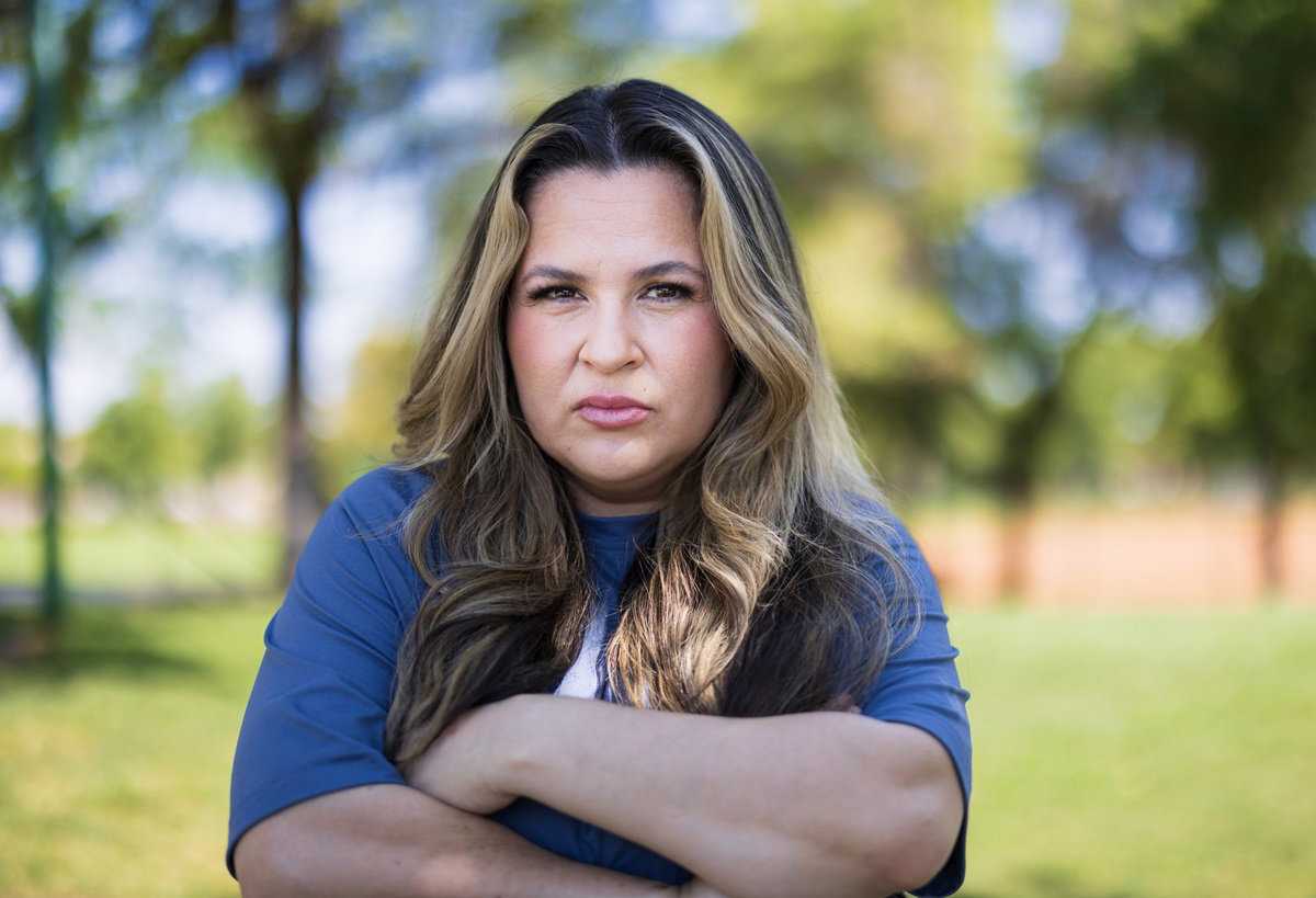 młoda kobieta z długimi włosami i z założonymi rękami stoi ze zmartwioną miną na dworze