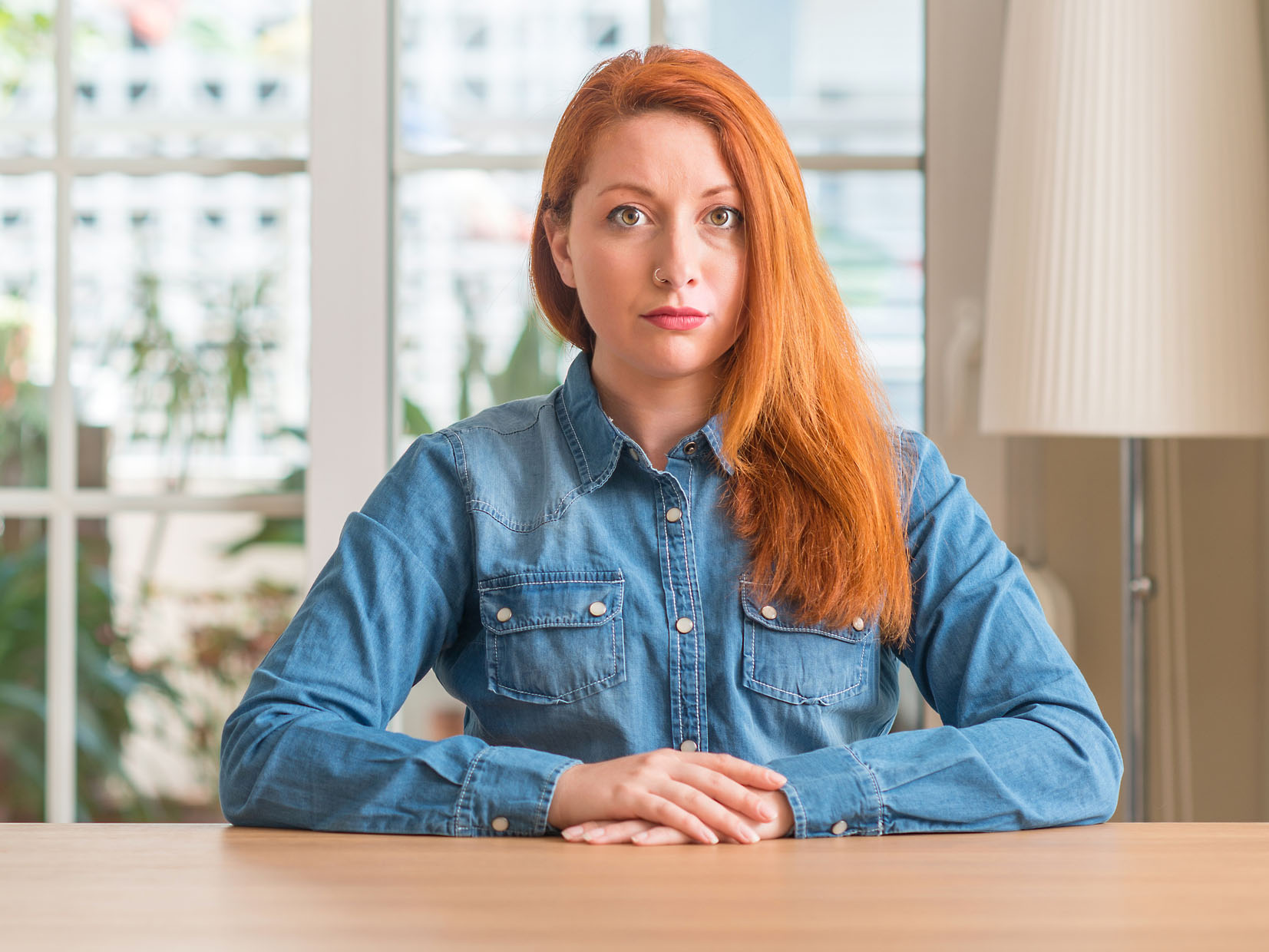 Redhead woman at home with serious expression on face. Simple and natural looking at the camera.