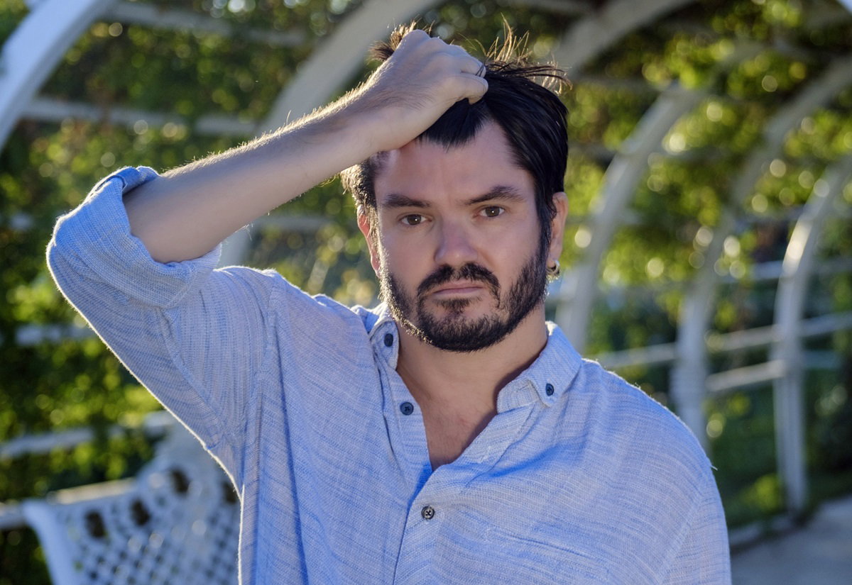 mężczyzna w średnim wieku stoi przy altanie i trzyma się za włosy ma przy tym zmartwioną minę