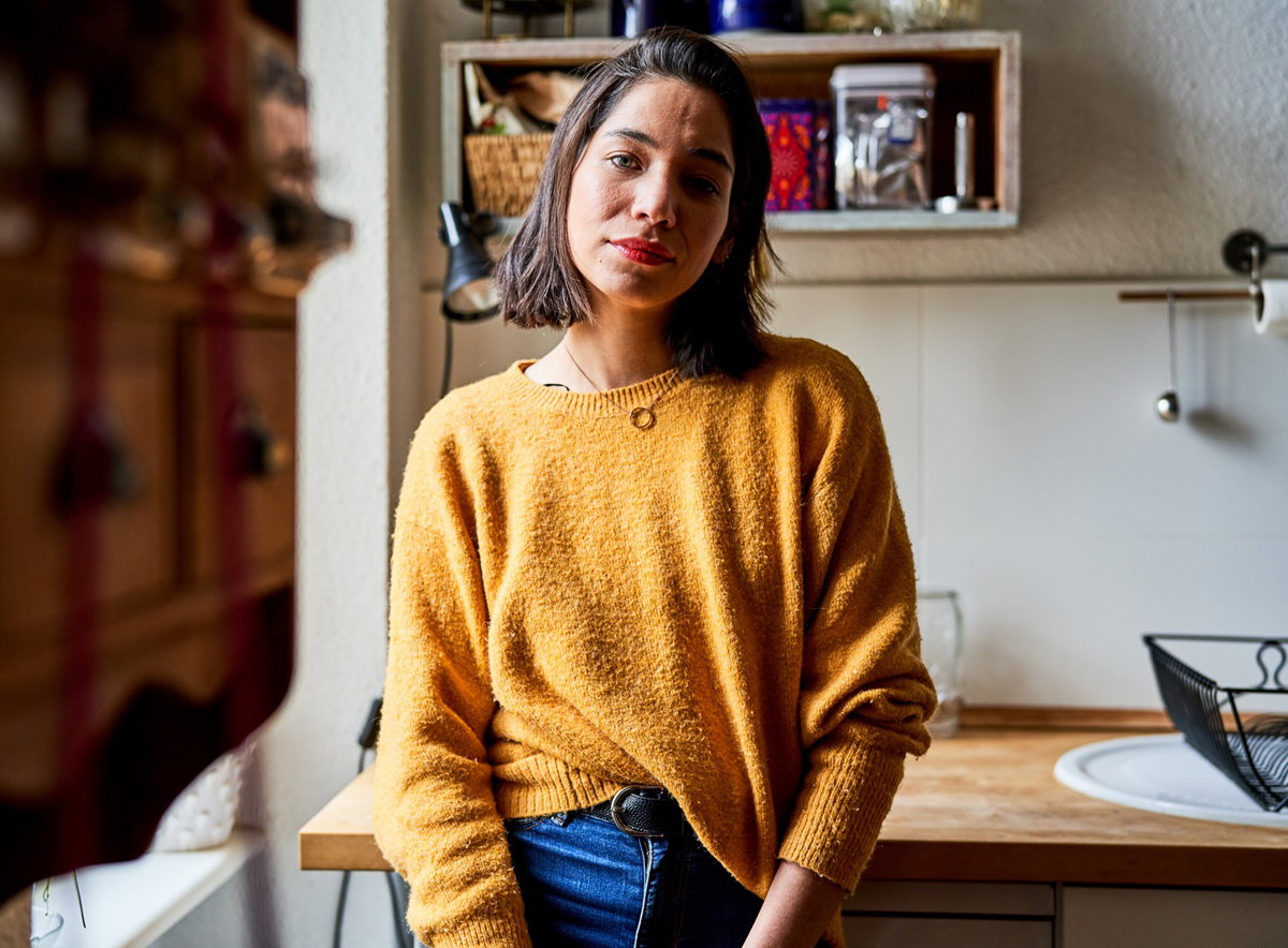 młoda kobieta w żółtym swetrze stoi na tle kuchni z zawiedzioną miną