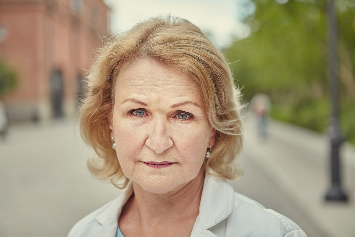 kobieta w wieku senioralnym z blond włosami patrzy przed siebie rozgoryczonym wzrokiem