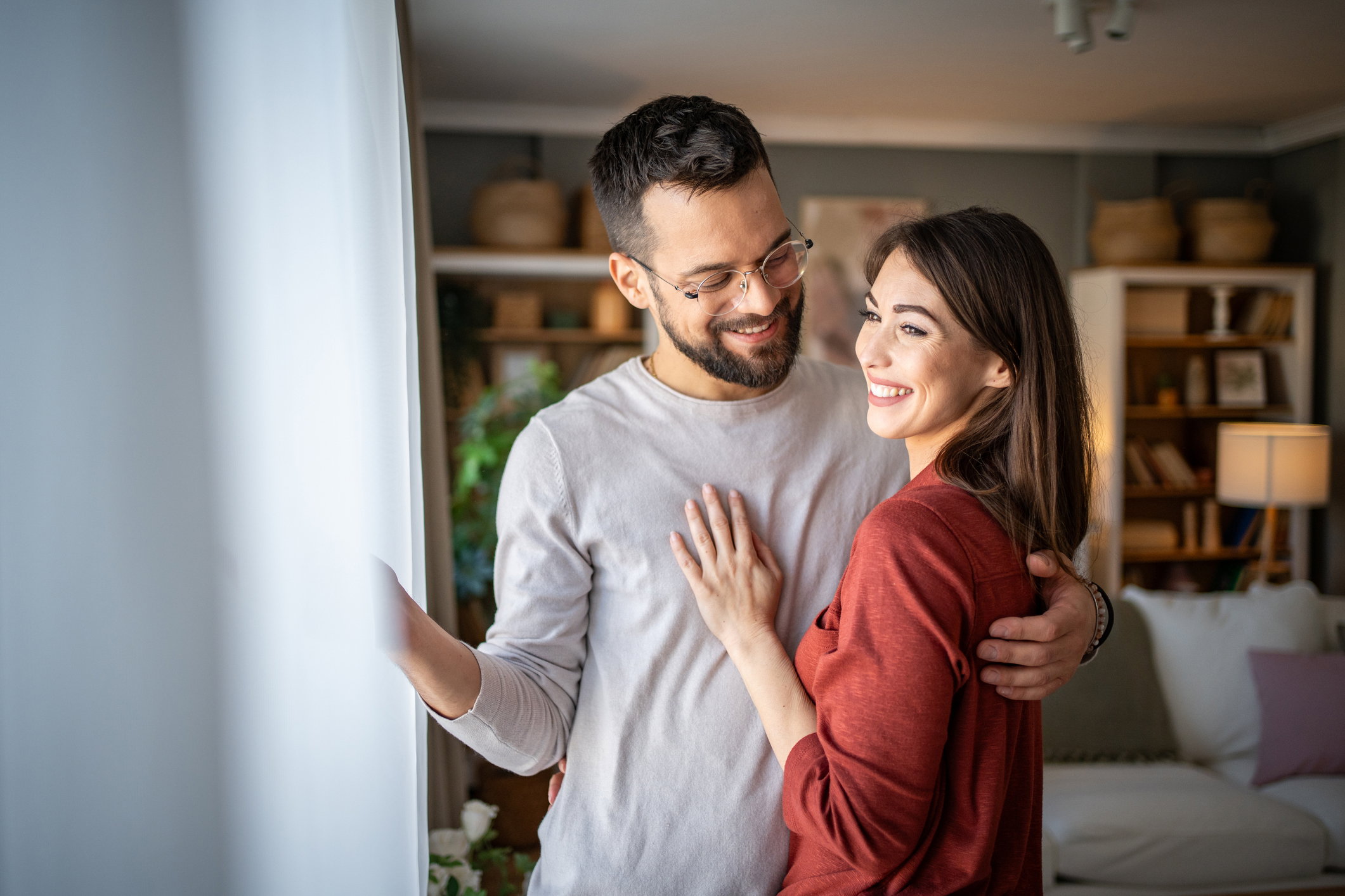 A wonderful scene of love and happiness between a couple in love standing embraced in their apartment