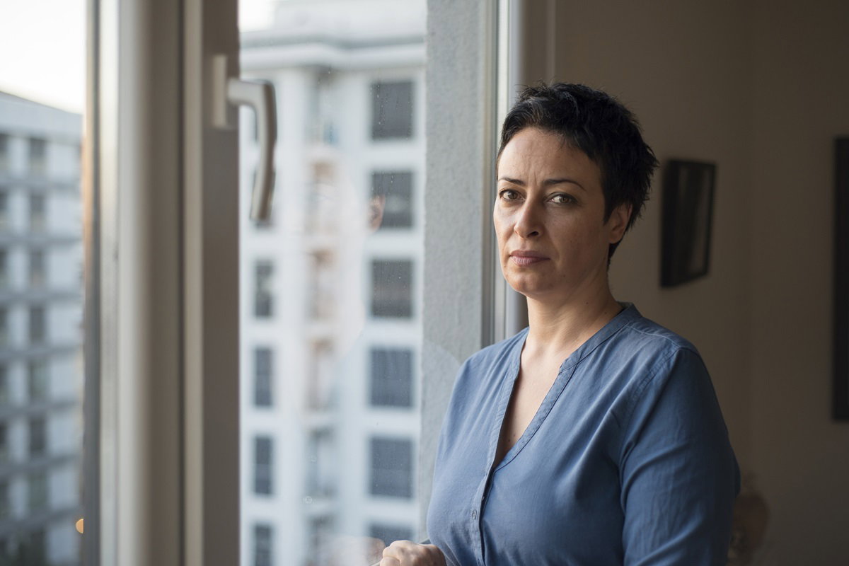 dojrzała kobieta stoi przy oknie ze zmartwioną miną