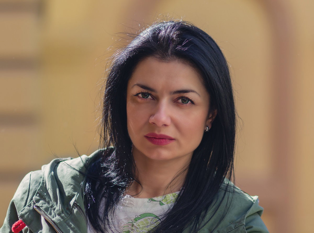 młoda kobieta w wieku około trzydziestu la z ciemnymi włosami patrzy przed siebie z rozgoryczeniem