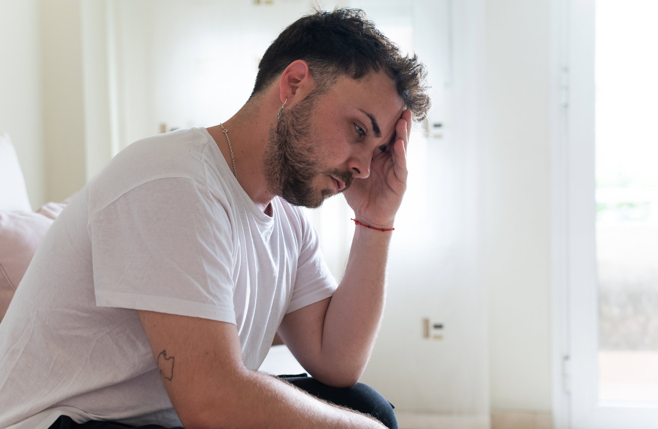 zmartwiony młody mężczyzna podpiera ręką głowę