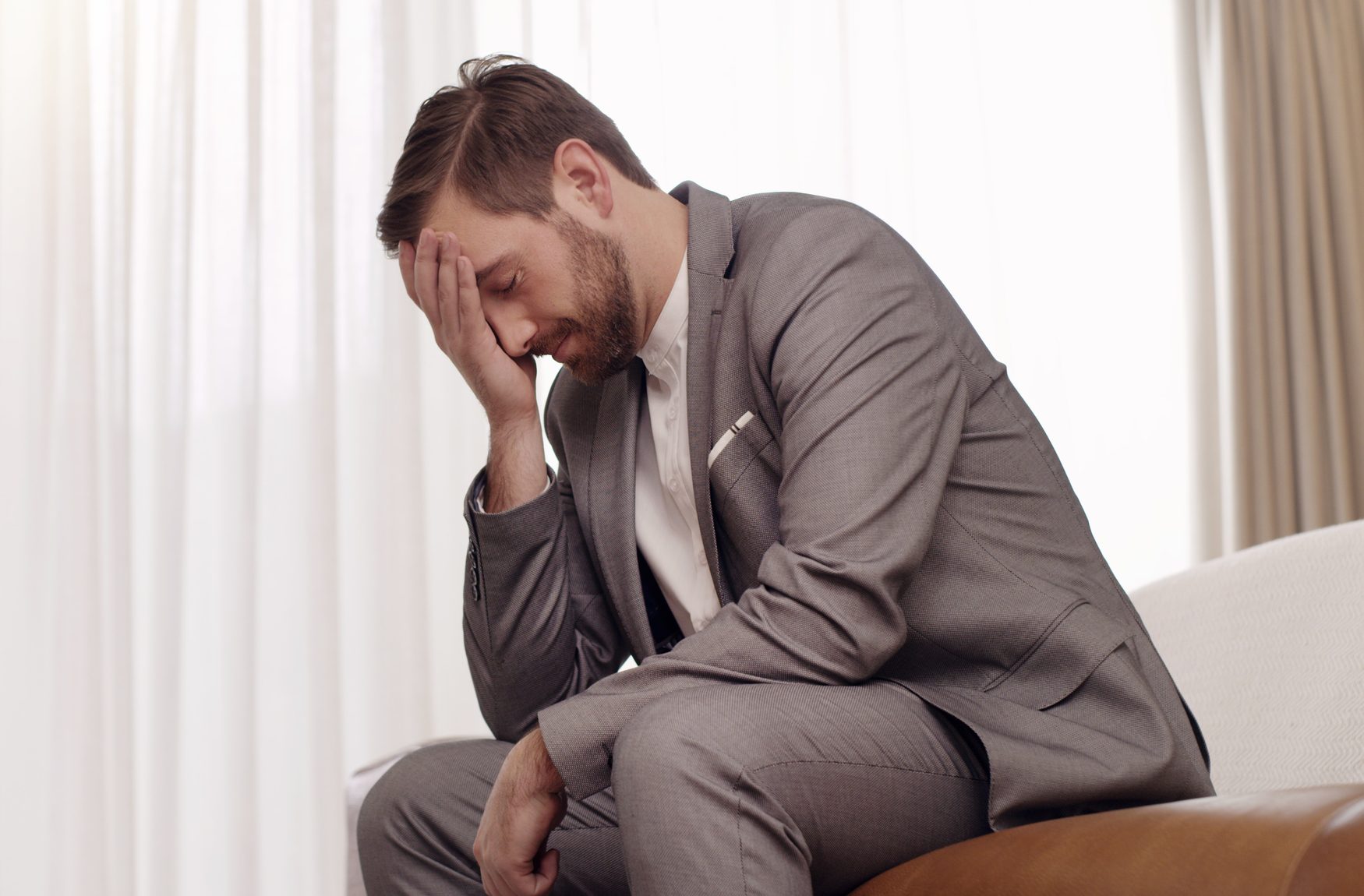 Frustrated business man with stress, anxiety and worry suffering after job loss or being fired due to recession or retrenchment. Unhappy and unemployed male worker sitting looking sad and depressed